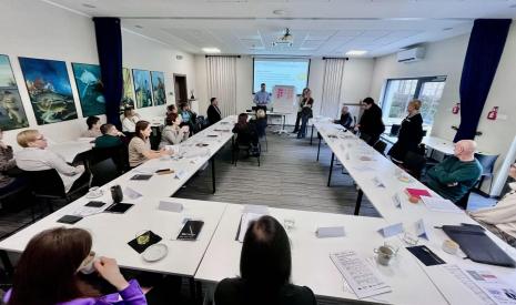 Ludzie siedzący wokół stołu na spotkaniu w jasnej sali konferencyjnej.