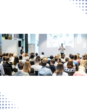 Ludzie siedzący na sali konferencyjnej, prelegent mówi przy ekranie.